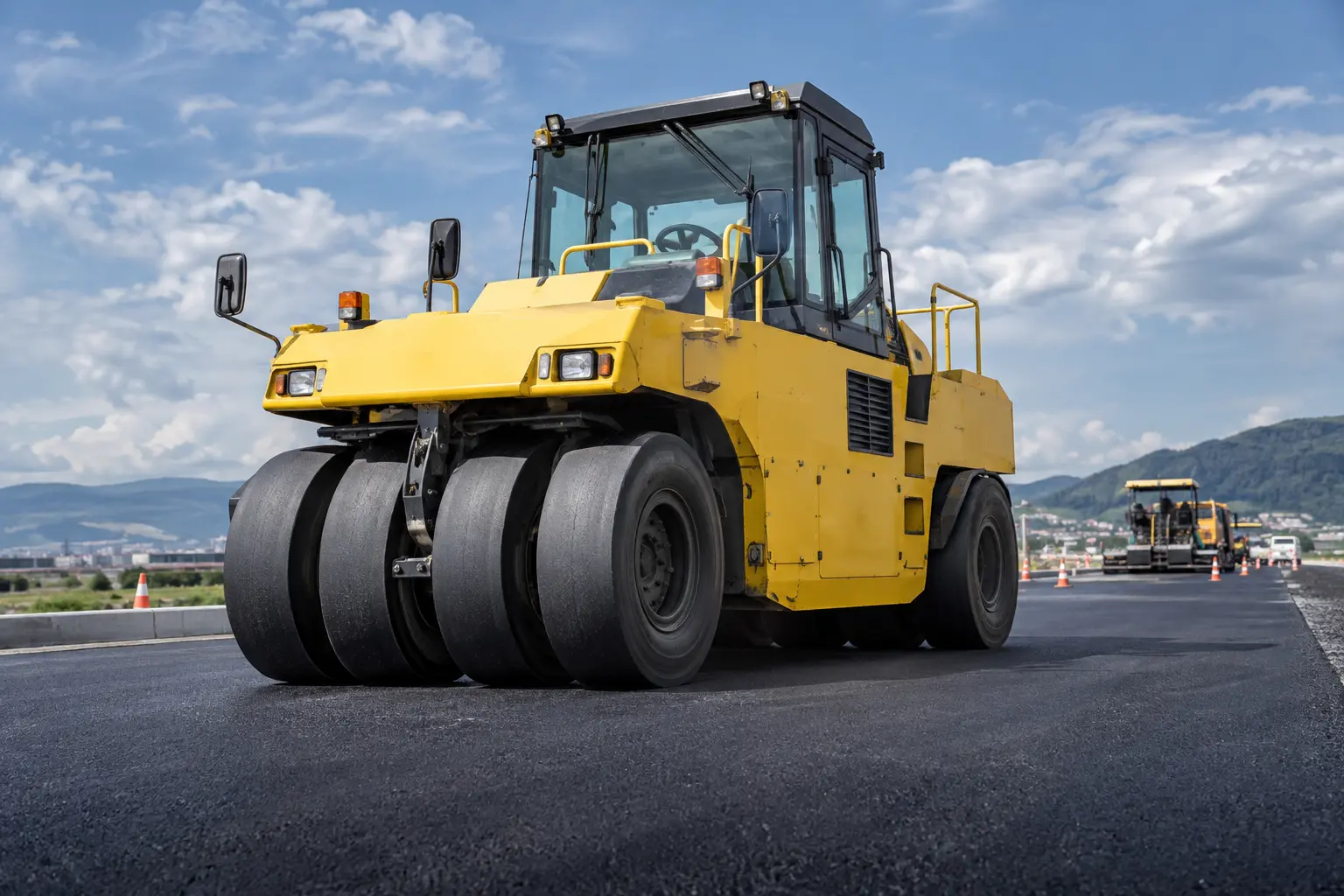 道路舗装工事でアスファルトを締め固める黄色いタイヤローラ